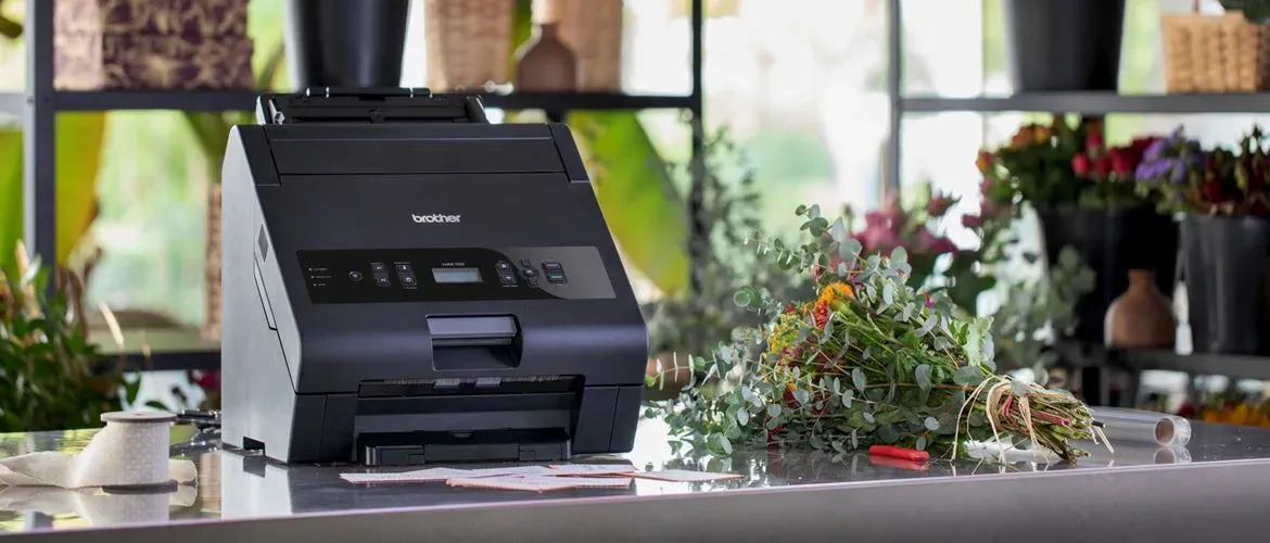 HAK hot foil printer, standing on table in flower shop, printed greeting cards and bouquet of flowers next to it at Brother Gulf, Middle East & Africa