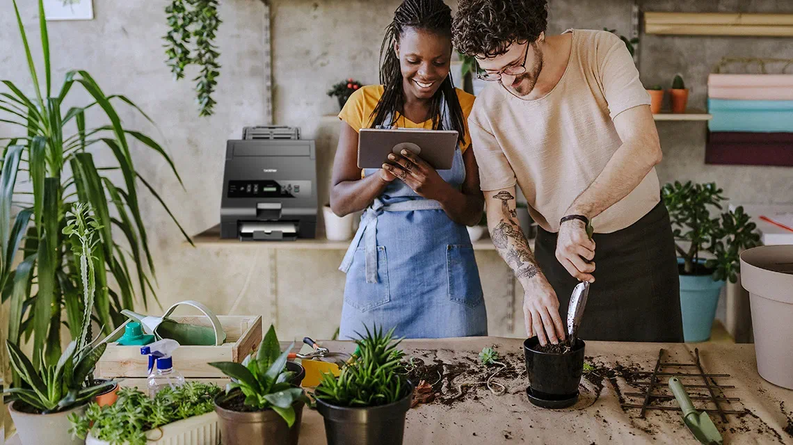 Woman and man in flower shop potting plants, HAK hot foil printer in the background at Brother Gulf, Middle East & Africa